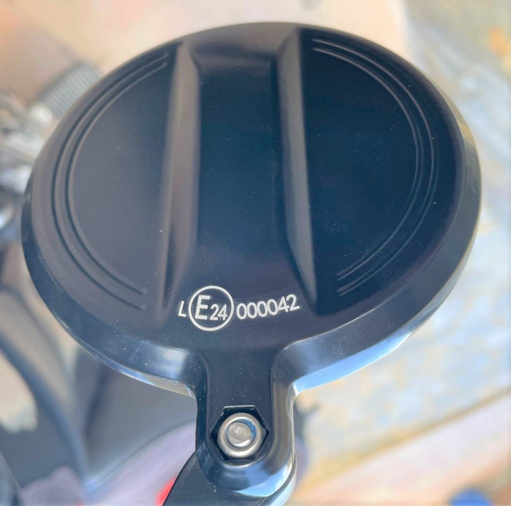 Imagen en primer plano de la parte trasera de un retrovisor de motocicleta, donde se observa el marcado de homologación europeo grabado en la carcasa: “E24 000042”. Este tipo de marcado indica que el retrovisor ha sido aprobado conforme a las normativas de la Unión Europea para componentes de vehículos. El código “E24” corresponde al país que ha emitido la homologación (Irlanda), y el número identifica la certificación específica. Ideal para verificar cumplimiento legal en revisiones técnicas o procesos de homologación.